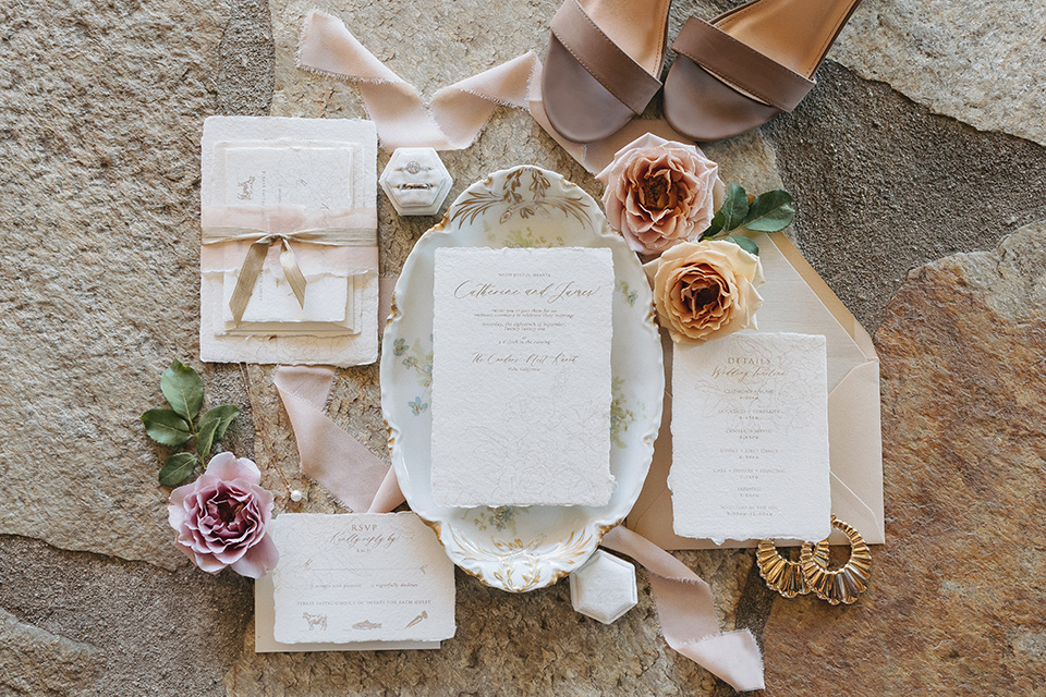  an elevated cottagecore wedding design in a barn venue with gold and tan tones – the bride in a white gown with long sleeves and the groom in a tan suit – invitations 