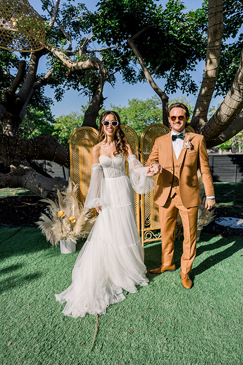  70s inspired wedding with orange and caramel tones with the bride in a lace gown and the groom in a caramel suit - ceremony 