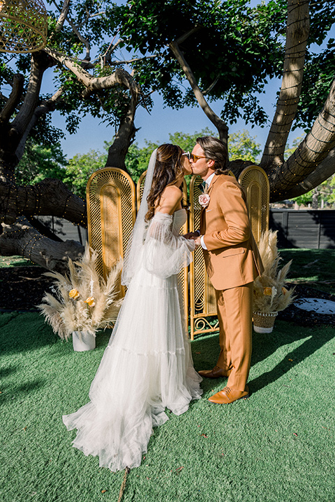  70s inspired wedding with orange and caramel tones with the bride in a lace gown and the groom in a caramel suit - ceremony 