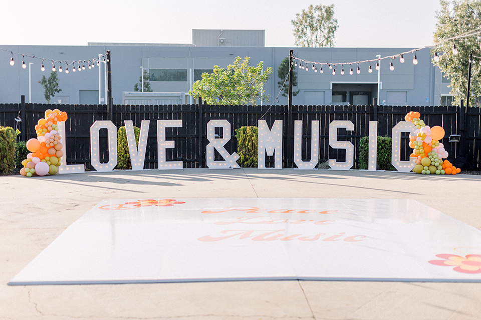  70s inspired wedding with orange and caramel tones with the bride in a lace gown and the groom in a caramel suit - marquee sign 