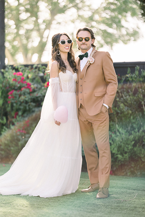  70s inspired wedding with orange and caramel tones with the bride in a lace gown and the groom in a caramel suit - couple smiling outside 