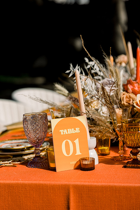  70s inspired wedding with orange and caramel tones with the bride in a lace gown and the groom in a caramel suit - table decor 