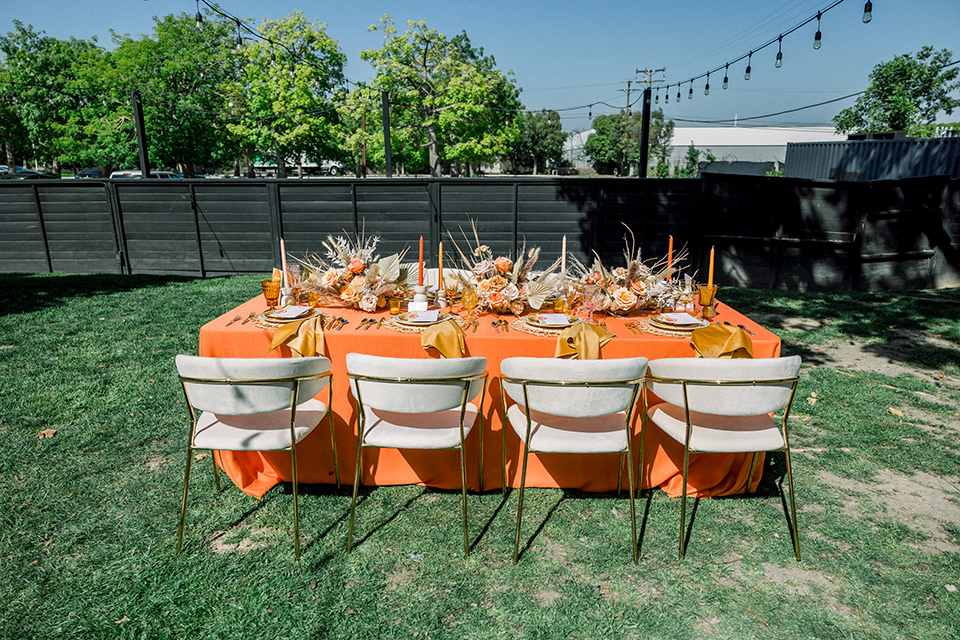  70s inspired wedding with orange and caramel tones with the bride in a lace gown and the groom in a caramel suit - outside 