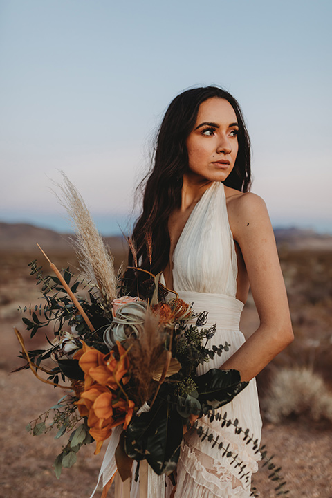  a boho elopement at the seven magical mountains in Las Vegas – the bride in a boho gown and the groom in a rose pink suit