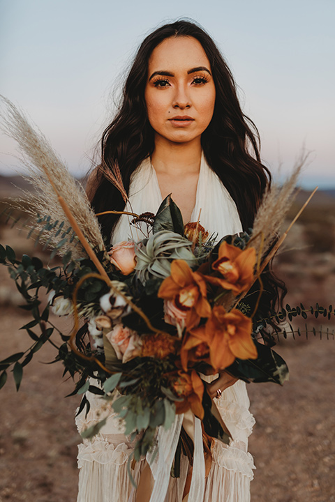  a boho elopement at the seven magical mountains in Las Vegas – the bride in a boho gown and the groom in a rose pink suit 