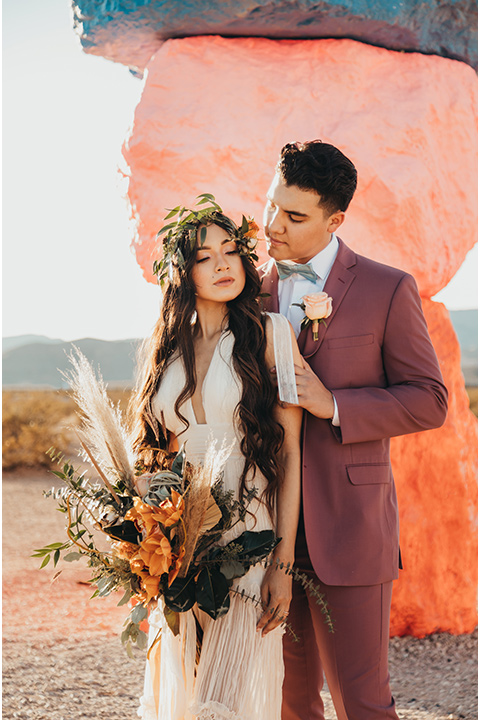  a boho elopement at the seven magical mountains in Las Vegas – the bride in a boho gown and the groom in a rose pink suit