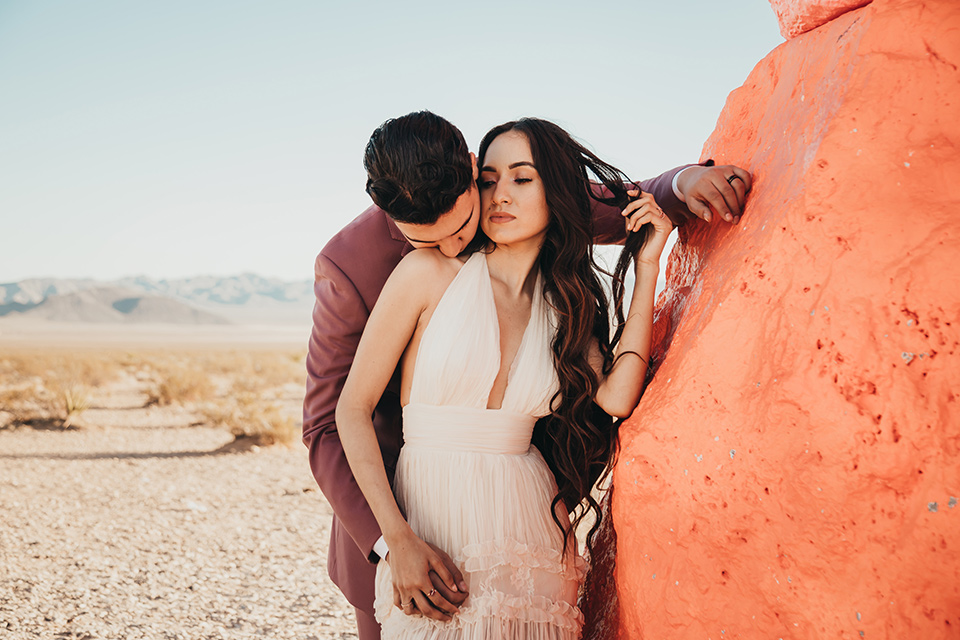  a boho elopement at the seven magical mountains in Las Vegas – the bride in a boho gown and the groom in a rose pink suit 