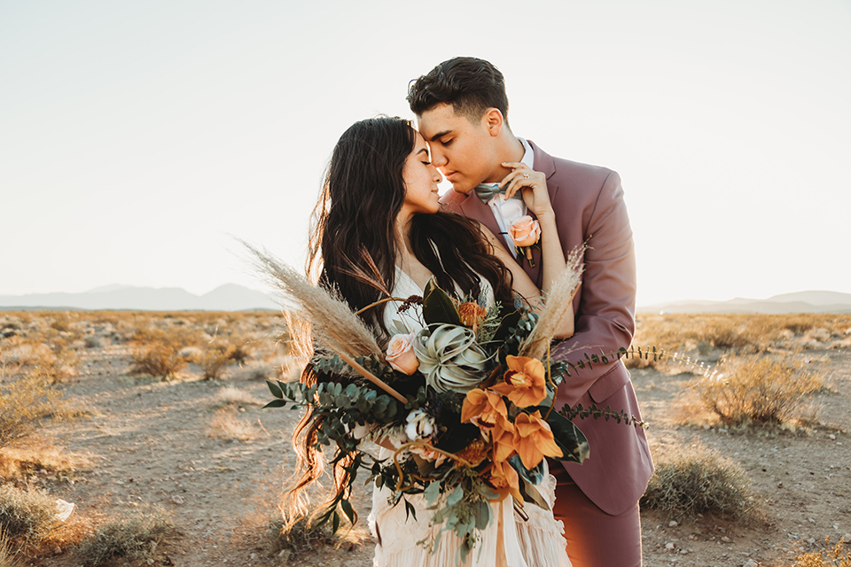  a boho elopement at the seven magical mountains in Las Vegas – the bride in a boho gown and the groom in a rose pink suit 