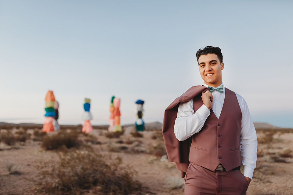  a boho elopement at the seven magical mountains in Las Vegas – the bride in a boho gown and the groom in a rose pink suit 