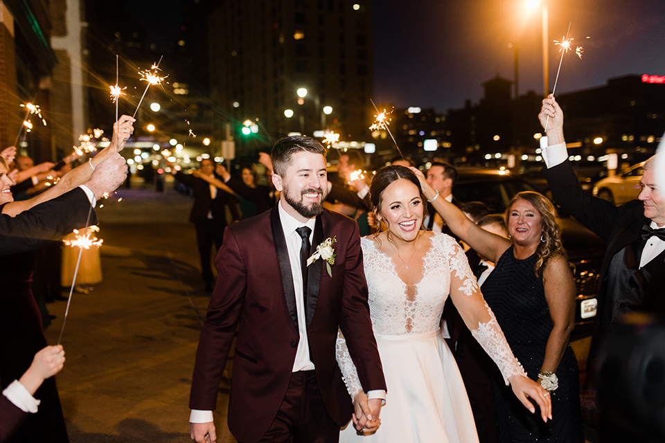  burgundy and green wedding with winter vibes - couple walking with sparklers 