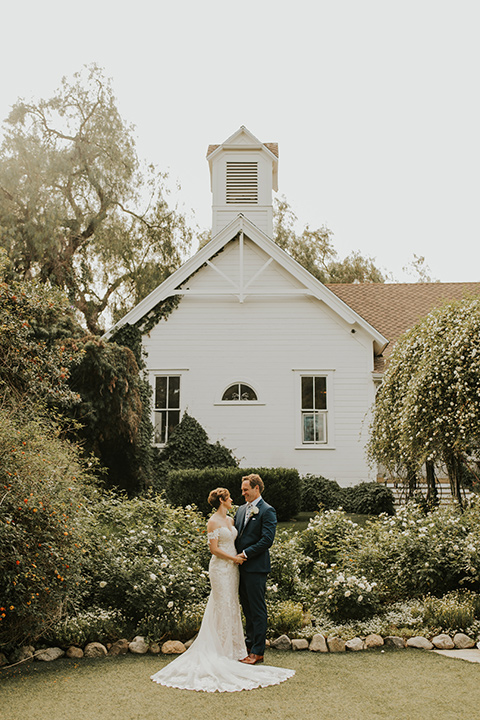  a romantic rustic garden wedding with the groom in a blue suit and floral tie and the bride in a lace gown - couple walking 