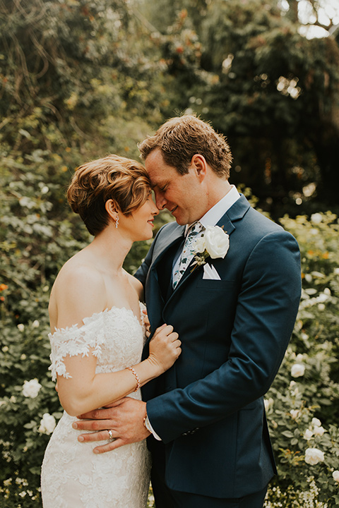  a romantic rustic garden wedding with the groom in a blue suit and floral tie and the bride in a lace gown - couple walking 