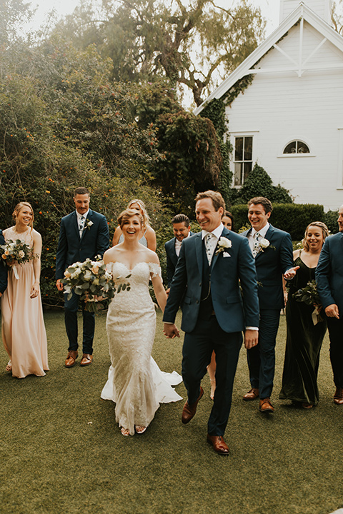  a romantic rustic garden wedding with the groom in a blue suit and floral tie and the bride in a lace gown - couple walking 