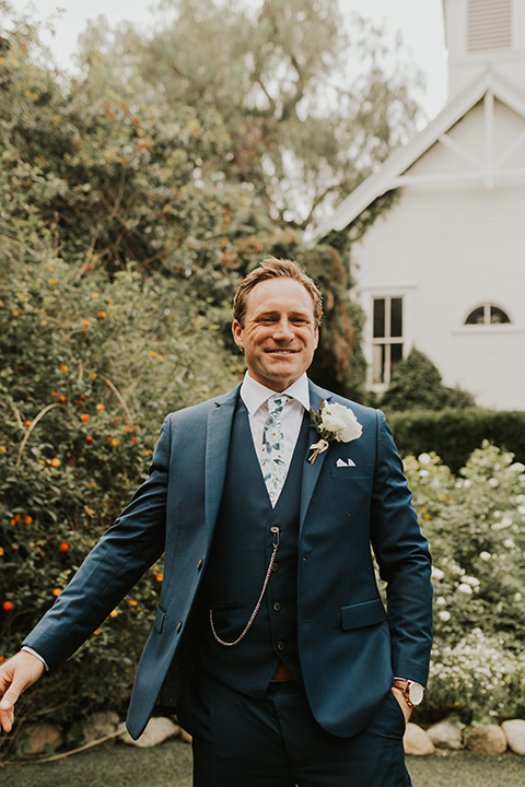  a romantic rustic garden wedding with the groom in a blue suit and floral tie and the bride in a lace gown - groom 