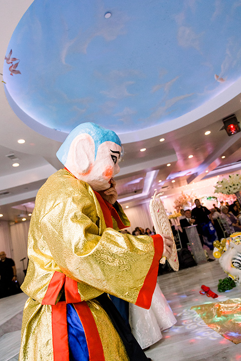  a grand cultural wedding with lion dancers and gold details – bride in a long gown with cape and groom in navy shawl tuxedo – wedding dancer 