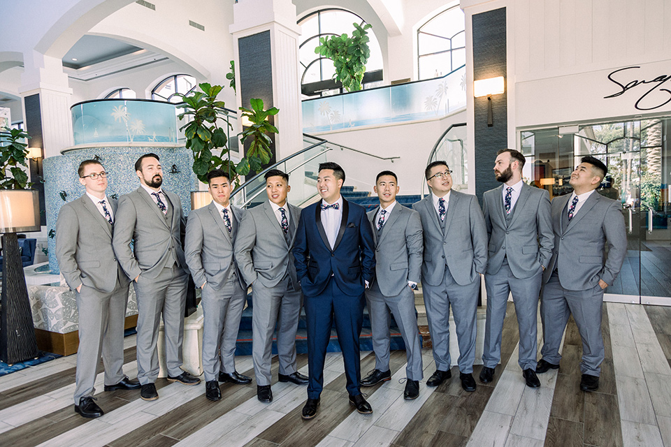  a grand cultural wedding with lion dancers and gold details – bride in a long gown with cape and groom in navy shawl tuxedo – groomsmen 