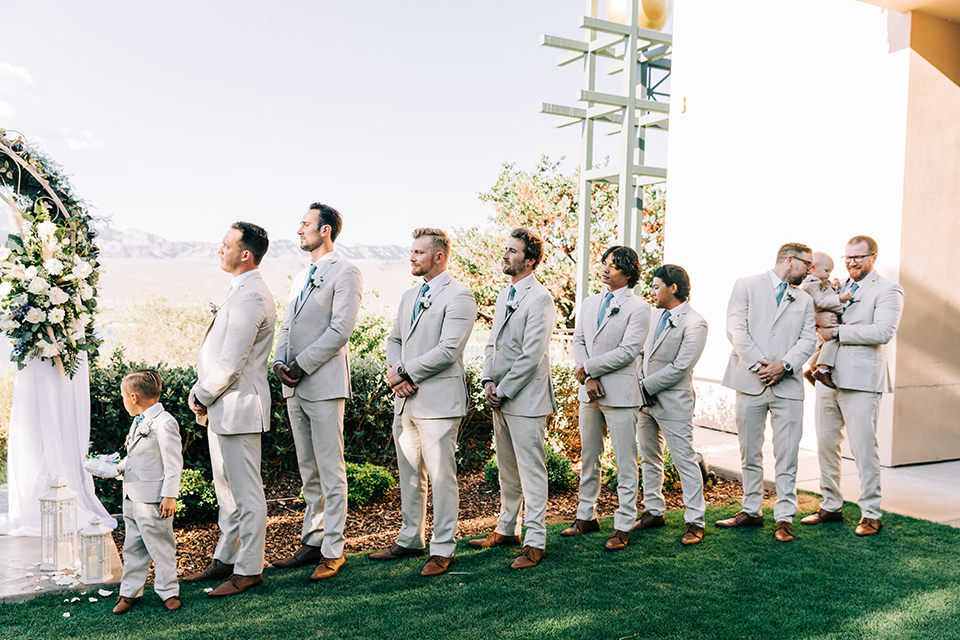  a tan and teal wedding with rustic chic details – groomsmen at ceremony 