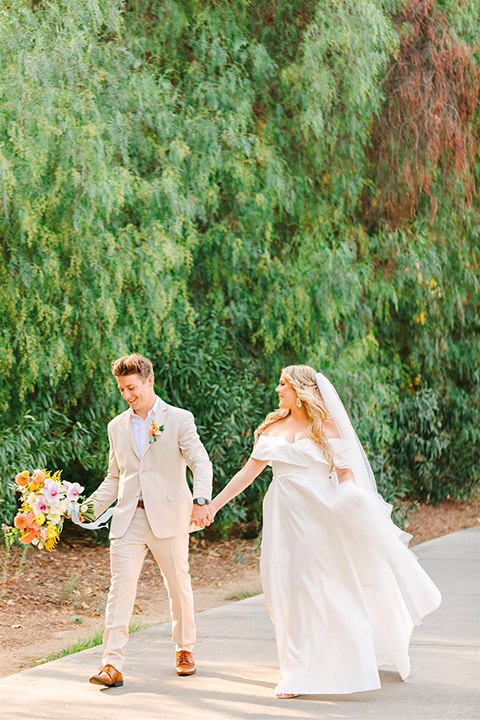  a beachy wedding with bold pastel colors and fun details - couple walking 