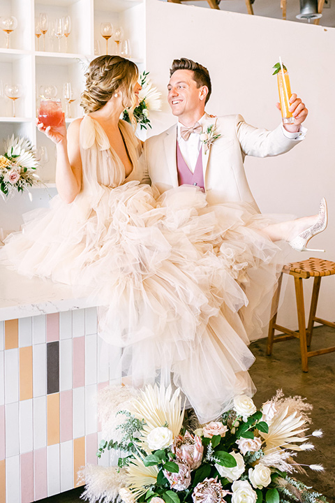  fun pink and champagne wedding with the bride in a pink tulle gown and the groom n a tan and pink look- couple at the bar 