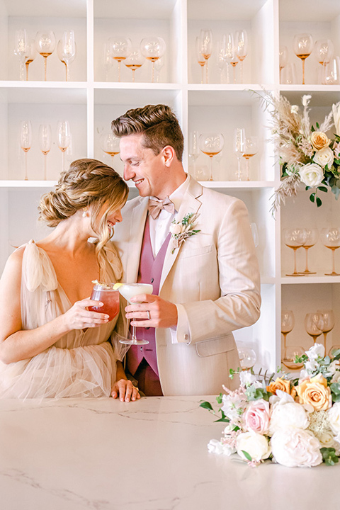  fun pink and champagne wedding with the bride in a pink tulle gown and the groom n a tan and pink look- couple at the bar 
