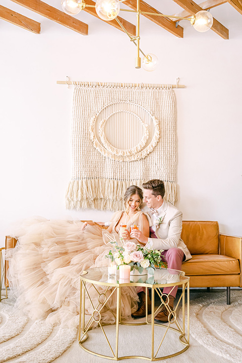  fun pink and champagne wedding with the bride in a pink tulle gown and the groom n a tan and pink look- couple sitting on the couch 