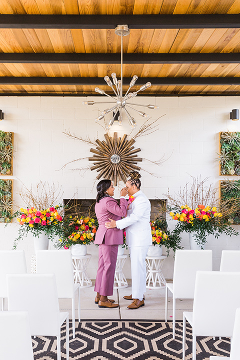 bright and bold lesbian wedding in Palm Springs with one bride in a rose pink suit and the other in a white suit – walking down the aisle 
