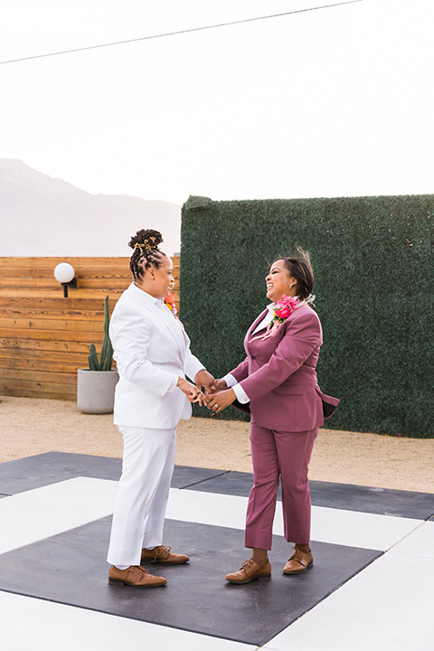  bright and bold lesbian wedding in Palm Springs with one bride in a rose pink suit and the other in a white suit – first dance