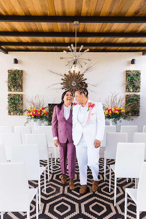  bright and bold lesbian wedding in Palm Springs with one bride in a rose pink suit and the other in a white suit – walking down the aisle