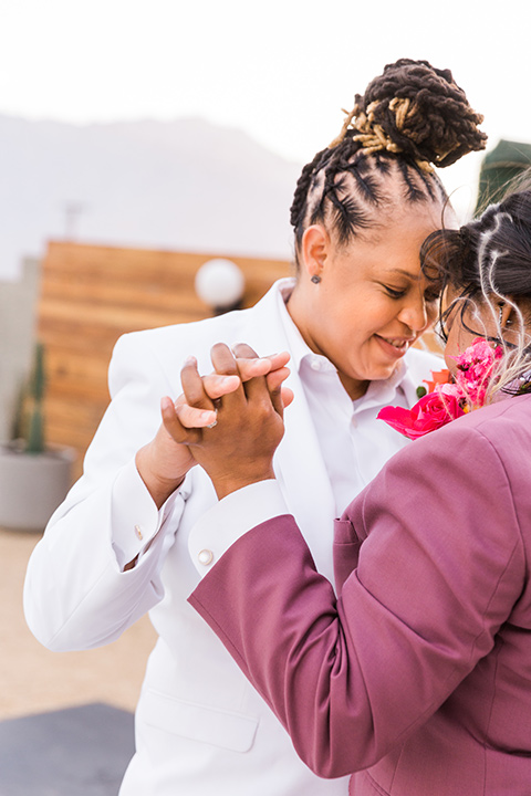  bright and bold lesbian wedding in Palm Springs with one bride in a rose pink suit and the other in a white suit – first dance 