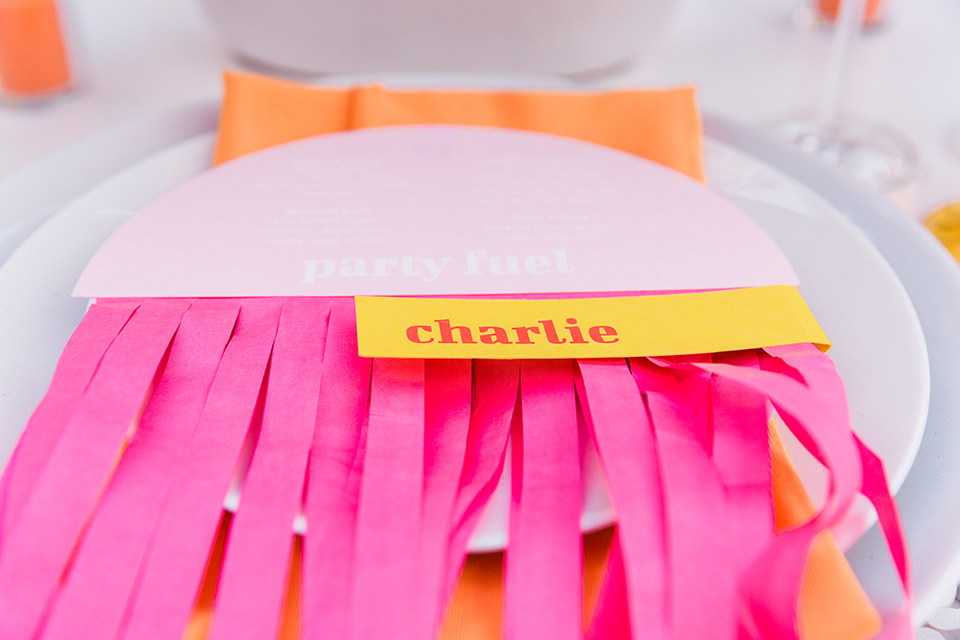  bright and bold lesbian wedding in Palm Springs with one bride in a rose pink suit and the other in a white suit – name cards