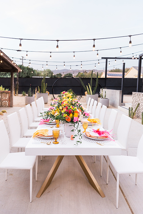  bright and bold lesbian wedding in Palm Springs with one bride in a rose pink suit and the other in a white suit – table decor 