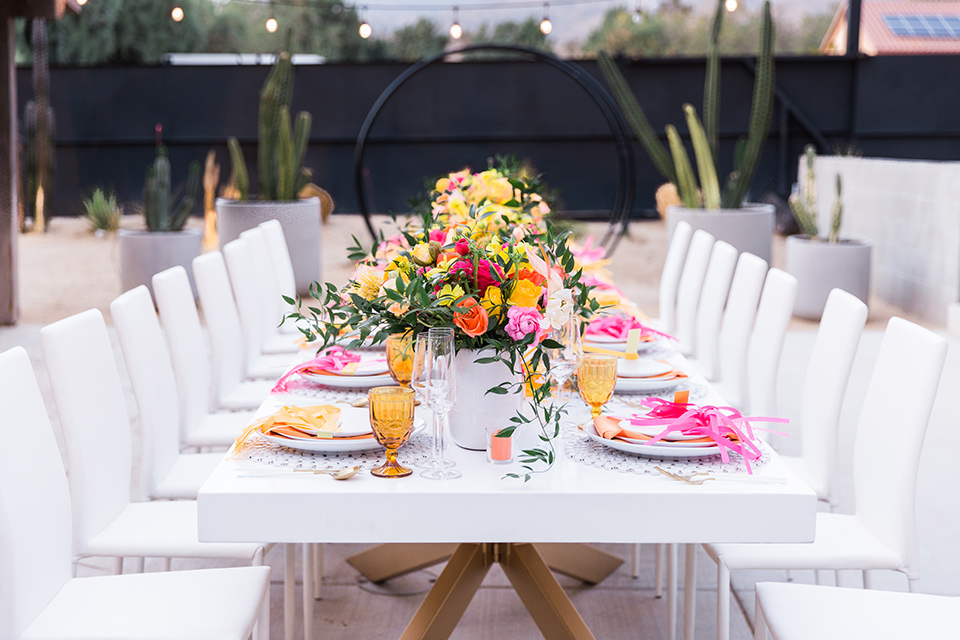  bright and bold lesbian wedding in Palm Springs with one bride in a rose pink suit and the other in a white suit – table decor