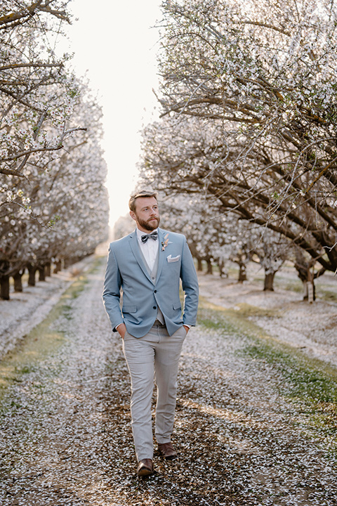  celestial cherry blossom wedding with the groom in a light blue coat and grey pants – groom