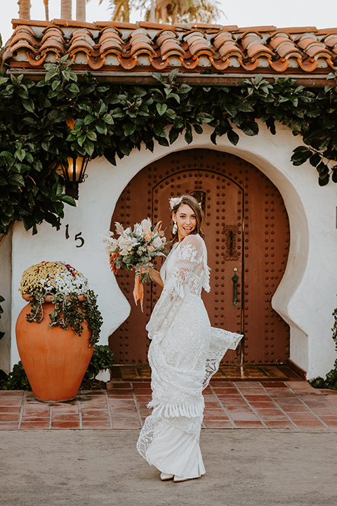  boho beach wedding with Spanish inspired architecture with the bride in a lace gown and the groom in a black tuxedo – bride