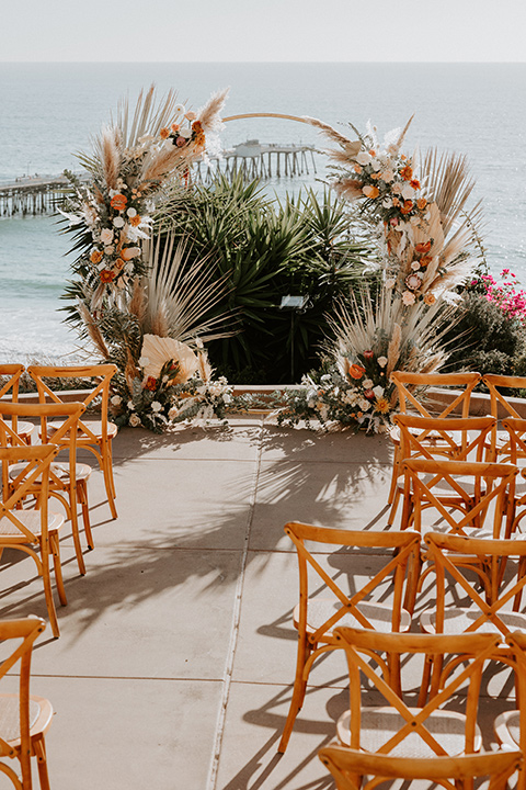  boho beach wedding with Spanish inspired architecture with the bride in a lace gown and the groom in a black tuxedo – ceremony decor