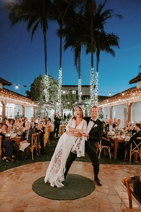  boho beach wedding with Spanish inspired architecture with the bride in a lace gown and the groom in a black tuxedo – first dance