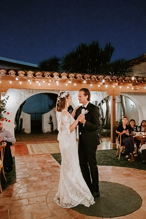  boho beach wedding with Spanish inspired architecture with the bride in a lace gown and the groom in a black tuxedo – first dance 