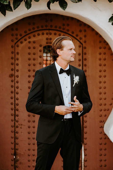  boho beach wedding with Spanish inspired architecture with the bride in a lace gown and the groom in a black tuxedo – groom