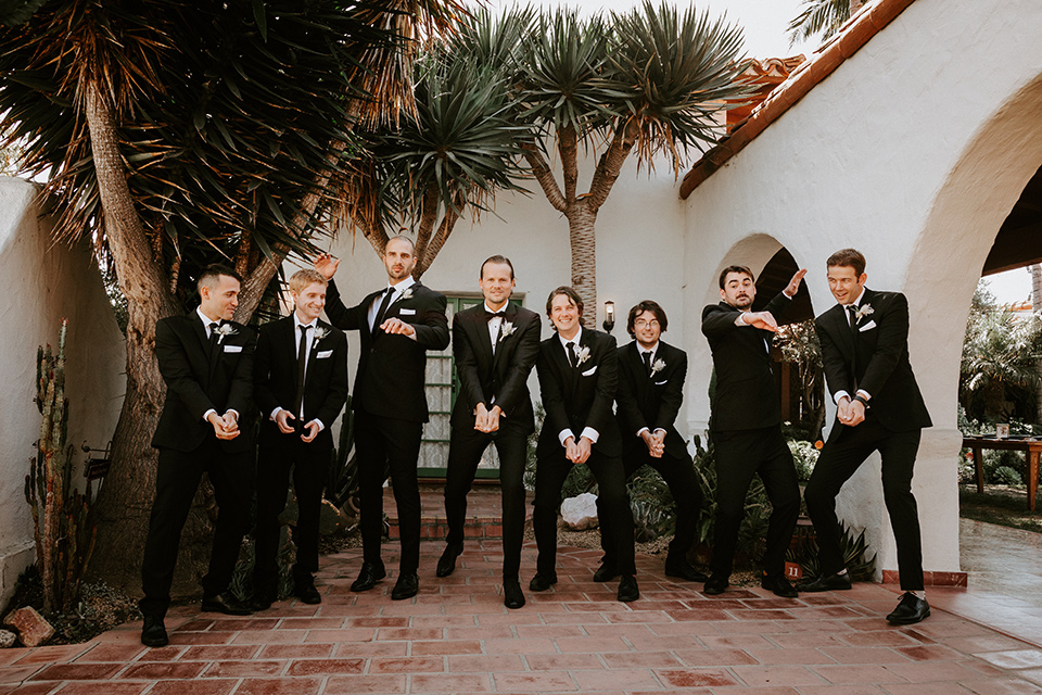  boho beach wedding with Spanish inspired architecture with the bride in a lace gown and the groom in a black tuxedo – groomsmen