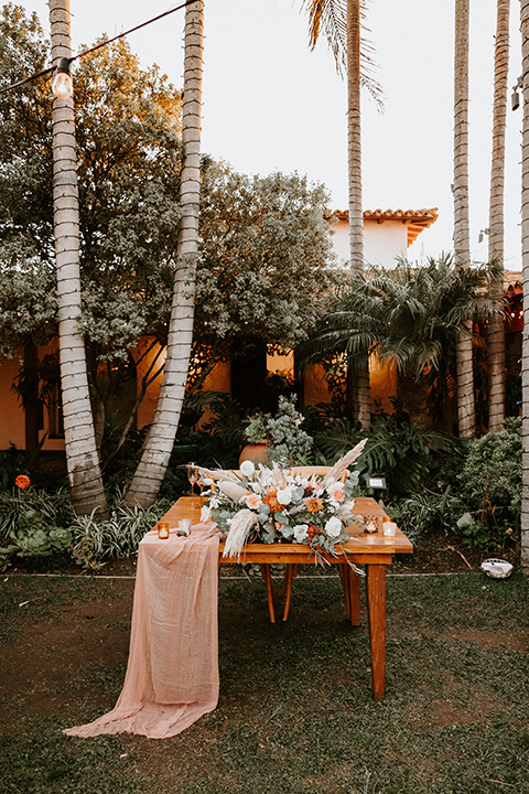  boho beach wedding with Spanish inspired architecture with the bride in a lace gown and the groom in a black tuxedo – sweetheart table