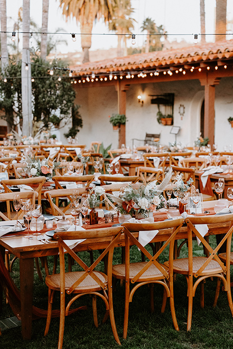  boho beach wedding with Spanish inspired architecture with the bride in a lace gown and the groom in a black tuxedo –tables 