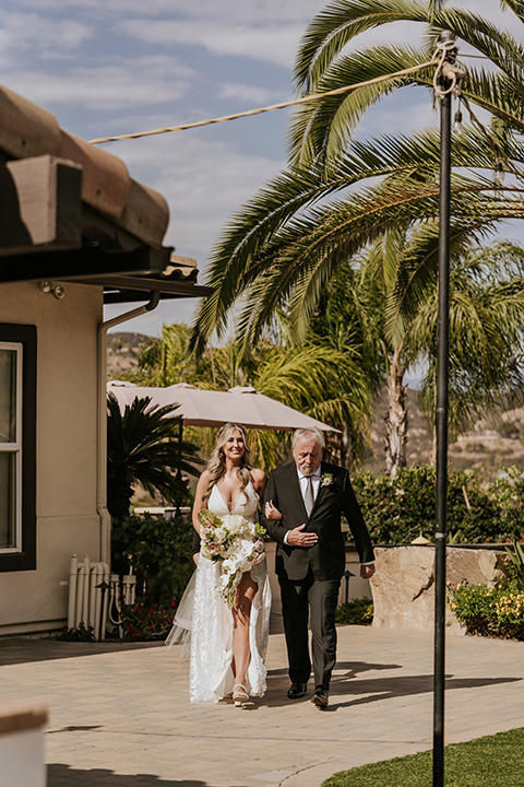  pink and black ranch wedding with elegant details - bride walking down the aisle and groom at the ceremony 
