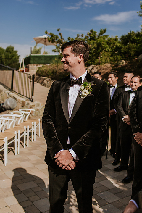  pink and black ranch wedding with elegant details - bride walking down the aisle and groom at the ceremony 