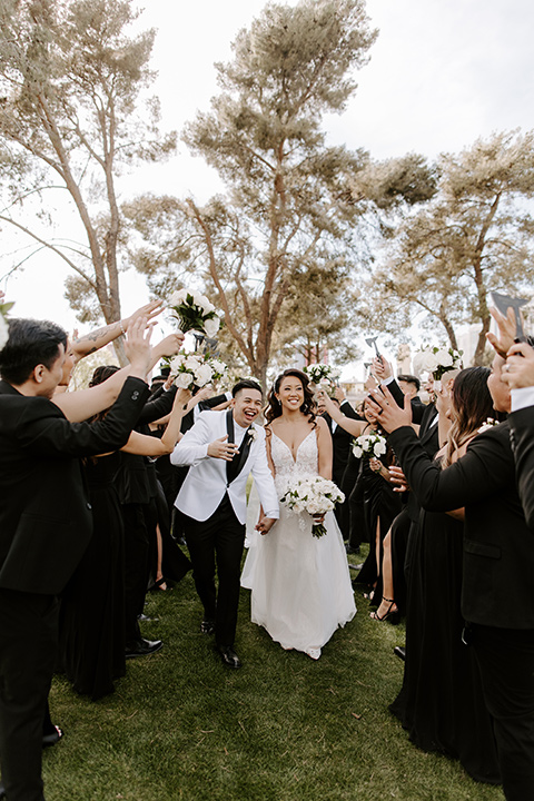  christine and gabes stunning black and white wedding with tropical touches – groom in a white tuxedo and groomsmen in black tuxedos