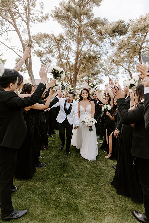  christine and gabes stunning black and white wedding with tropical touches – groom in a white tuxedo and groomsmen in black tuxedos 