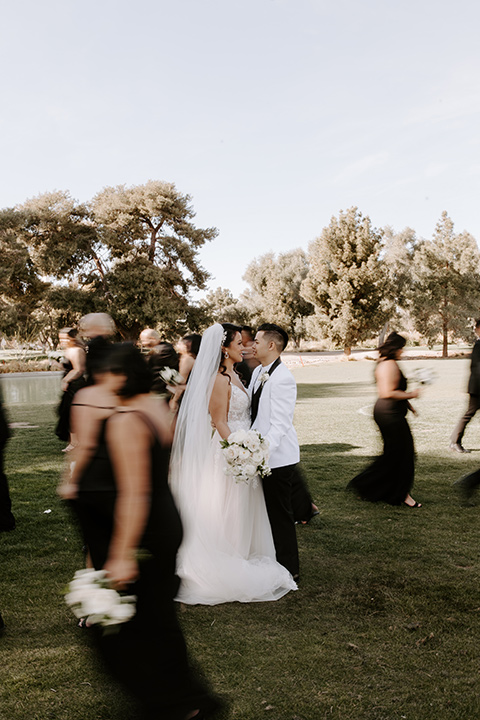  christine and gabes stunning black and white wedding with tropical touches – groom in a white tuxedo and groomsmen in black tuxedos