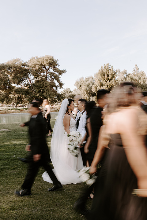  christine and gabes stunning black and white wedding with tropical touches – groom in a white tuxedo and groomsmen in black tuxedos 