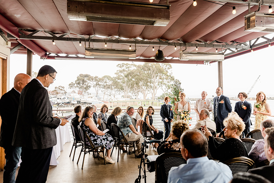  whimsical wedding at an ocean front venue with the groom in a mix and match look with navy and grey colors – ceremony