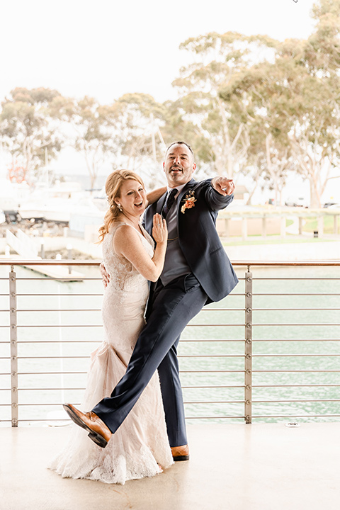  whimsical wedding at an ocean front venue with the groom in a mix and match look with navy and grey colors – couple laughing
