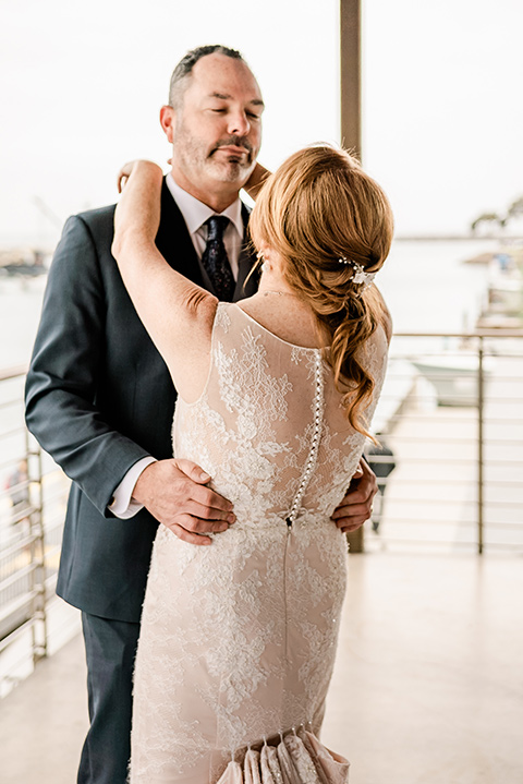  whimsical wedding at an ocean front venue with the groom in a mix and match look with navy and grey colors – couple embracing 